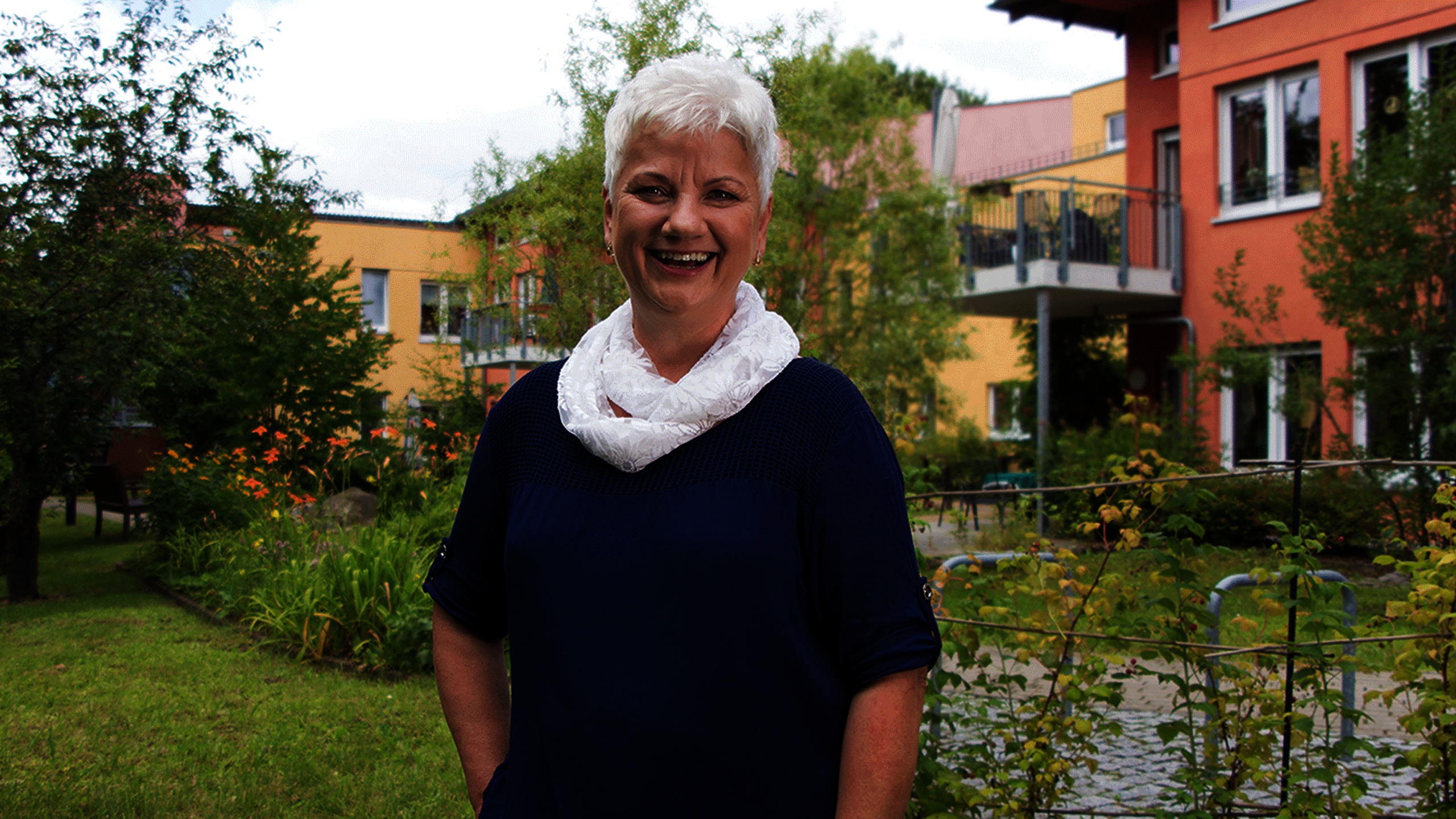 Marion Petersdorf steht im Garten vor Pflegewohnzentrum