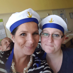 Steffi Rackwitz und Mitarbeiterin tragen Kapitänsmütze für Seefahrer